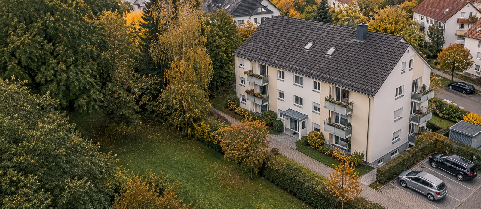 Wohngebäude mit Garten, Wegen und Stellplätzen aus der Vogelperspektive